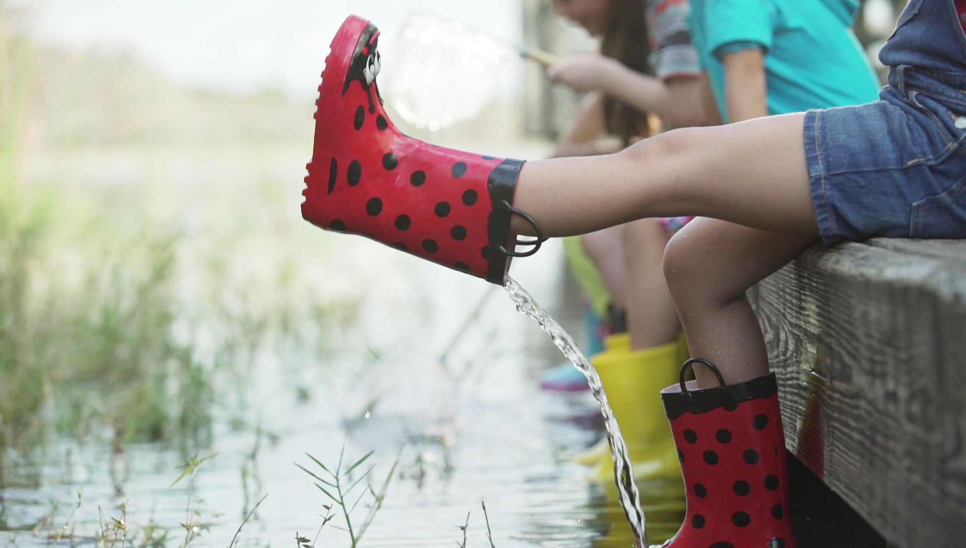 Child in boots playing in water